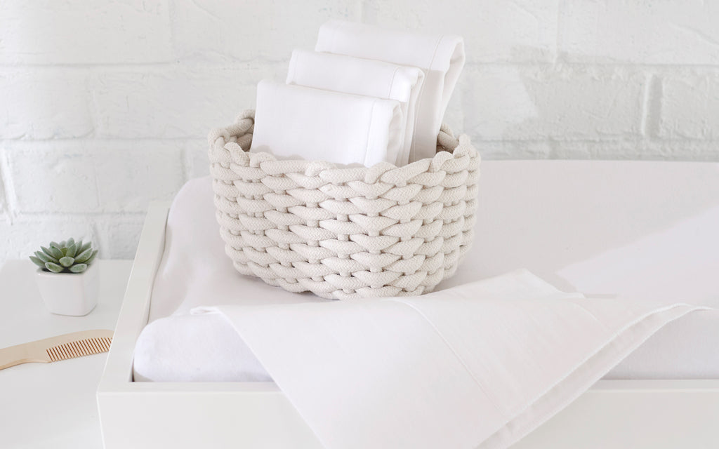 Luxurious white towels neatly arranged in a basket, adding a touch of elegance to a cozy baby changing pad..