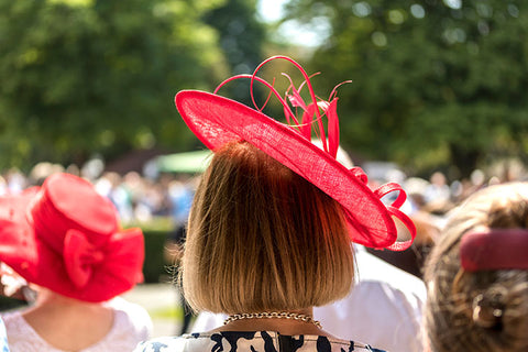 Lady at a racing event wearing a magenta fascinator.