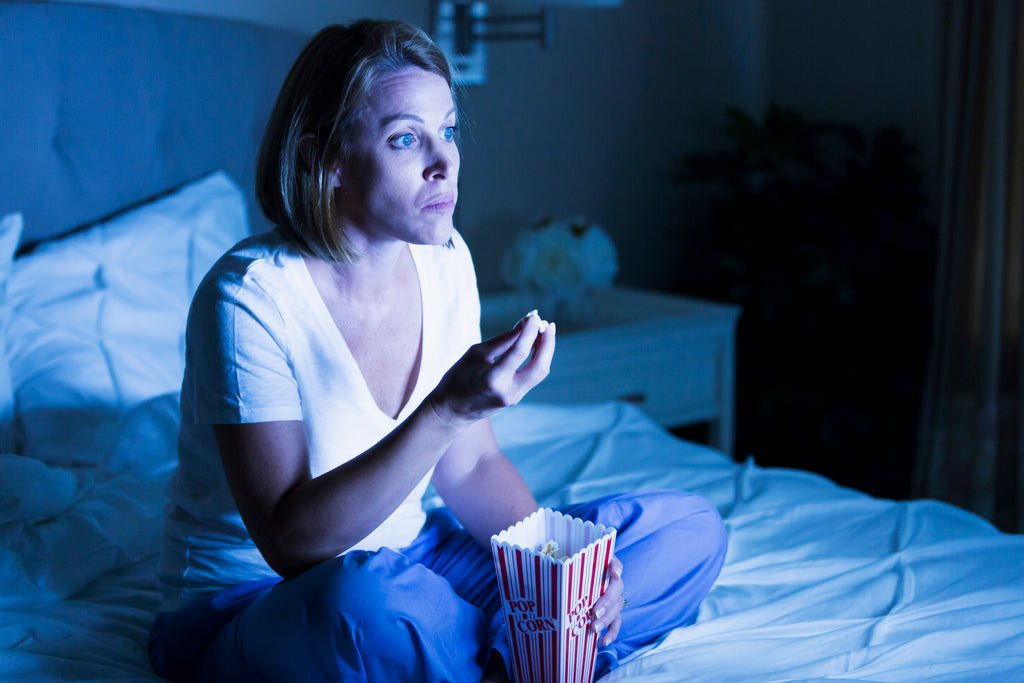 Woman eating popcorn exploring what to watch when you can't sleep