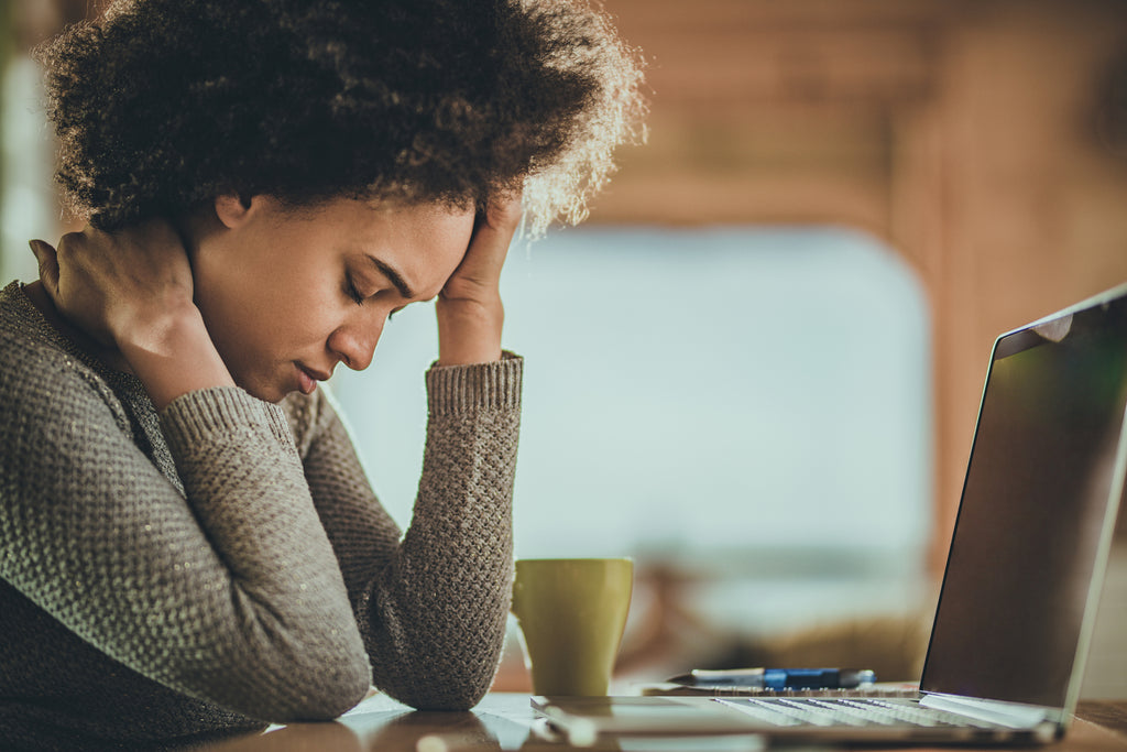 woman with adrenal fatigue with headache and coffee at laptop