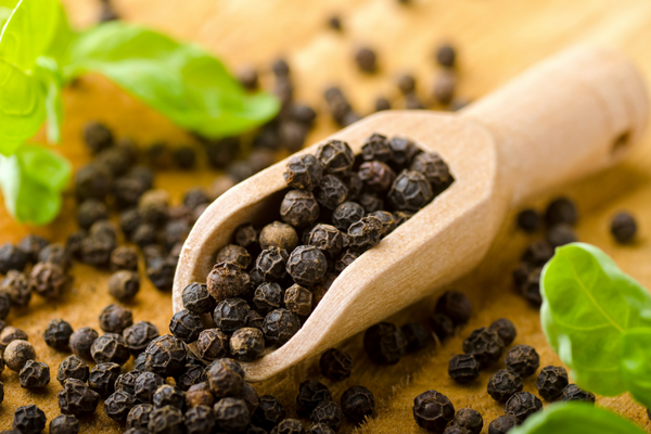 black peppercorns with a wooden spoon