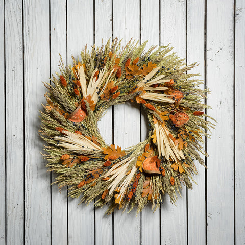 22" wreath made of corn husk, phalaris, natural flax, maple leaves, and dried quince slices on a white wood fence background.