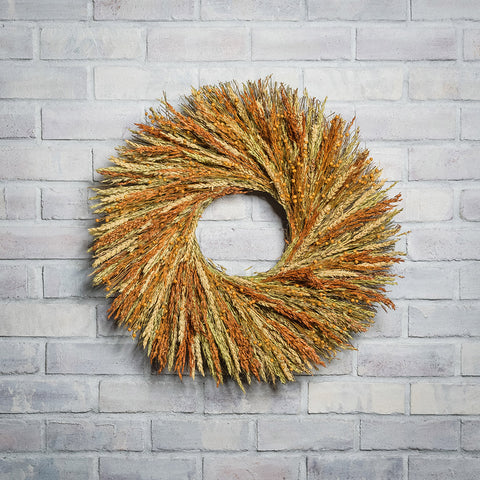 22" wreath of sudan grass, dijon sudan, saffron flax, and natural wheat on a white brick background.
