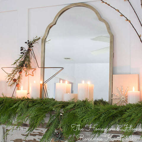 Green Western Red Cedar garland draped across a mantle with candles and mirror. 