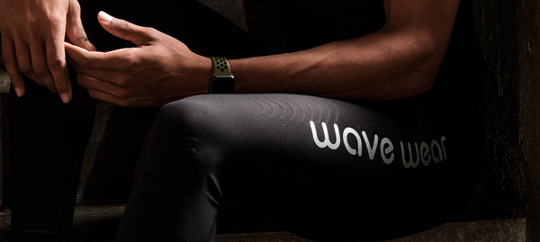 man sitting in the dark wearing wavewear leggings, close up on the logo