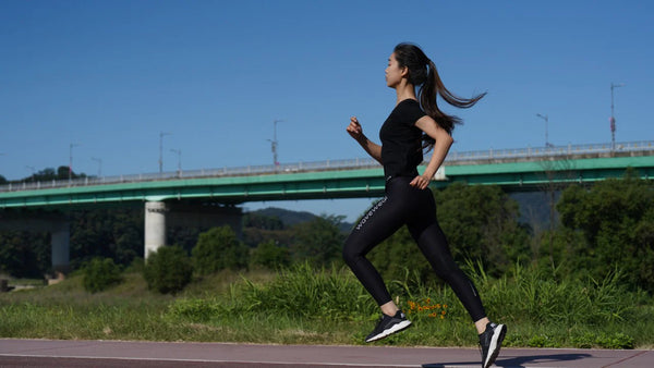 Woman mid run down a path wearing the wavewear woman's compression leggings