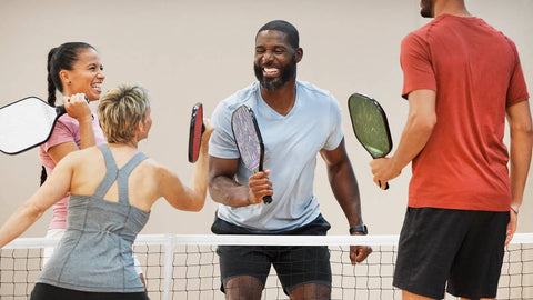 A team of four pickle ball players congratulating by the net