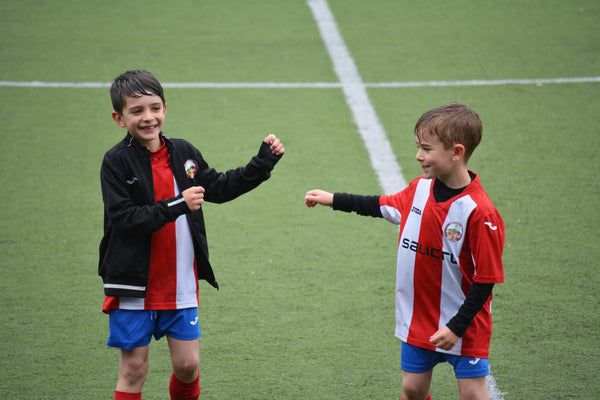 two little kids on a soccer field congratulating