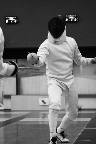 Man standing at the ready in a fencing uniform