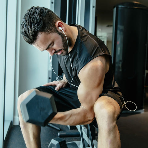 Man sitting on workout bench curling a weight for his right arm bicep curls