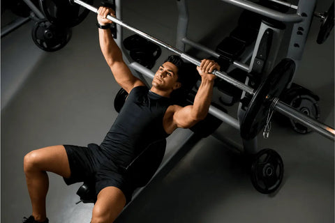 man in a gym laying back and doing some bench presses