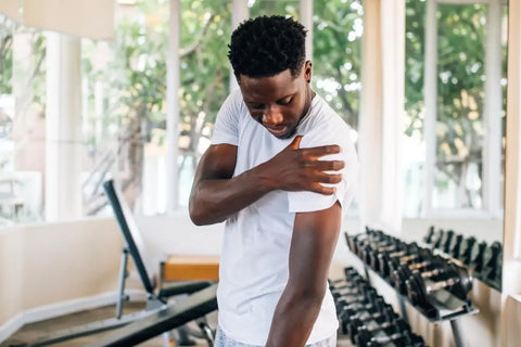 man in a gym holding his arm as if he was in pain or distress