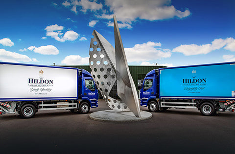 HIldon Lorries (both royal blue cabs, one Hildon Sparkling/white the other Hildon still/ blue )parked either side of silver sculpture at Hildon HQ.