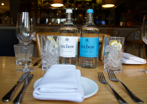 Restaurant table laid with two bottles of Hildon natural mineral water