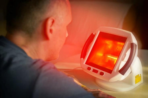 A man treating sinuses with red light therapy lamp