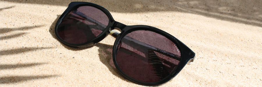 Sunglasses on a beach with palm tree shadow