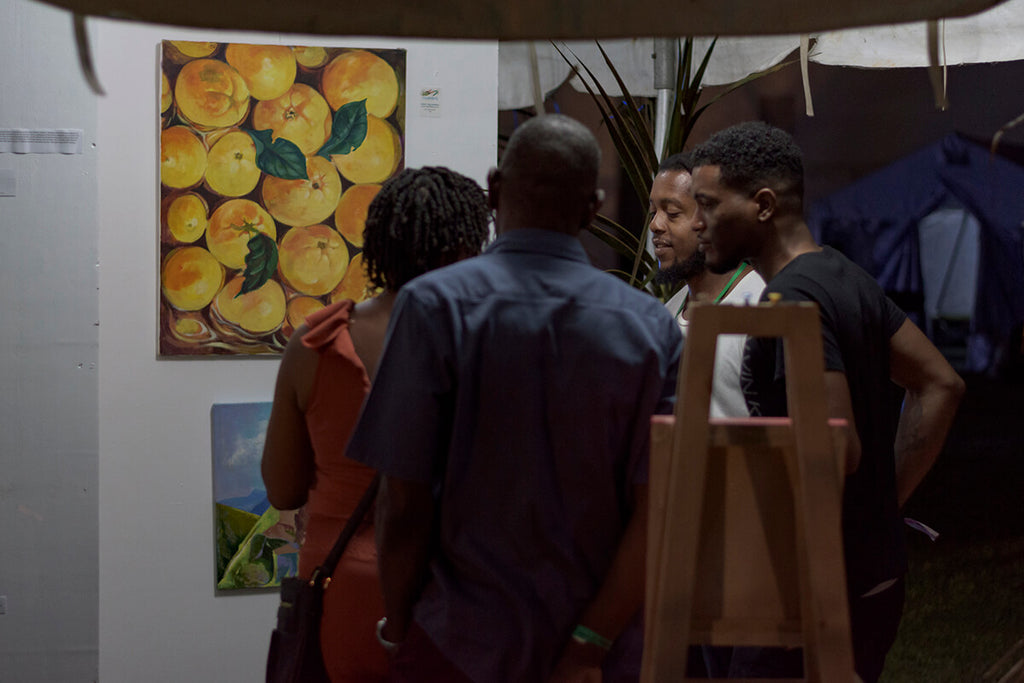 Artist, Shadrach Burton, explaining his art in the Art Gallery section of the VIP area, WCMF, 2019