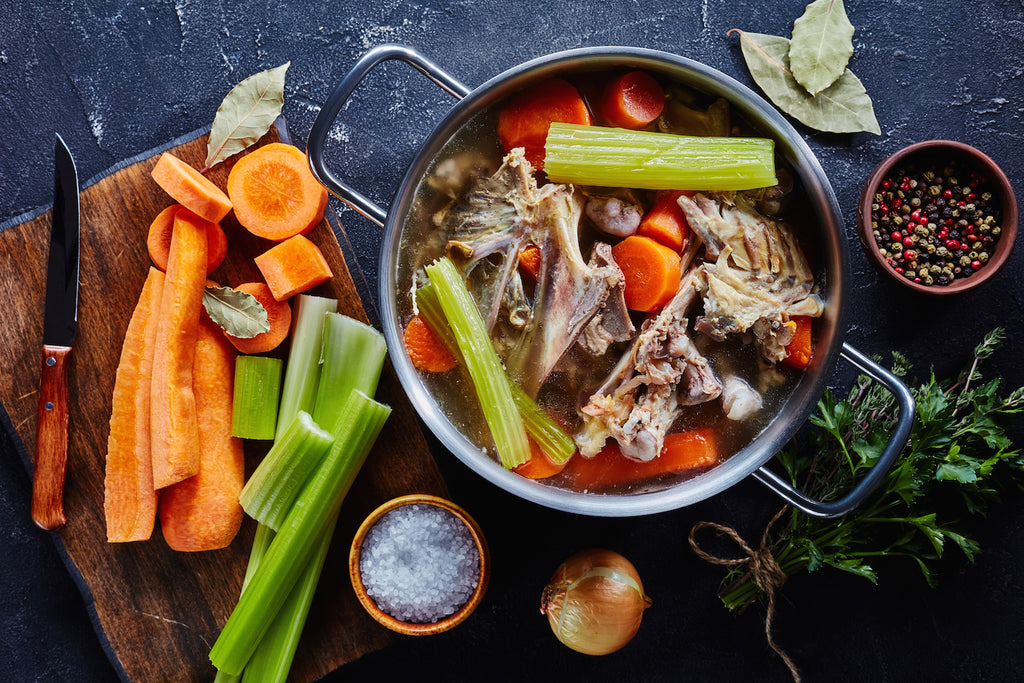 Bone broth before cooking with vegetables and herbs scattered