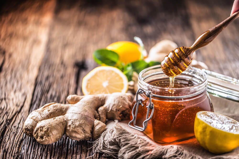 is honey paleo: a jar of honey with some ginger and lemon on a table