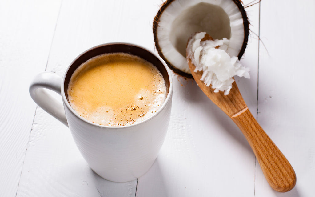 Cup of coffee with coconut and coconut oil on a wooden spoon