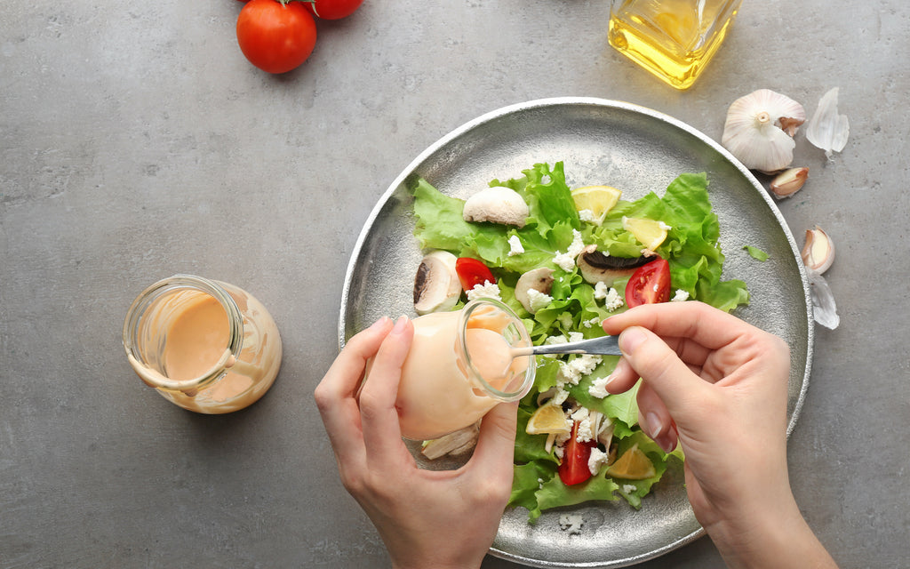 keto mayonnaise: Woman adding dressing to a fresh salad