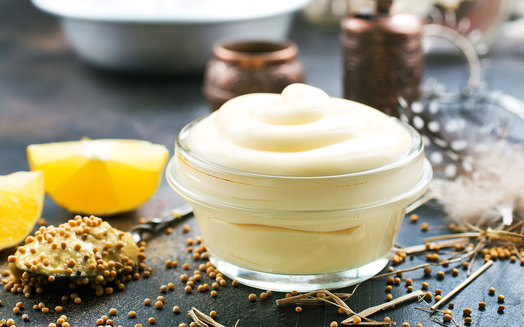 olive oil mayonnaise: Mayonnaise in a small glass bowl with lemon, herbs and spices