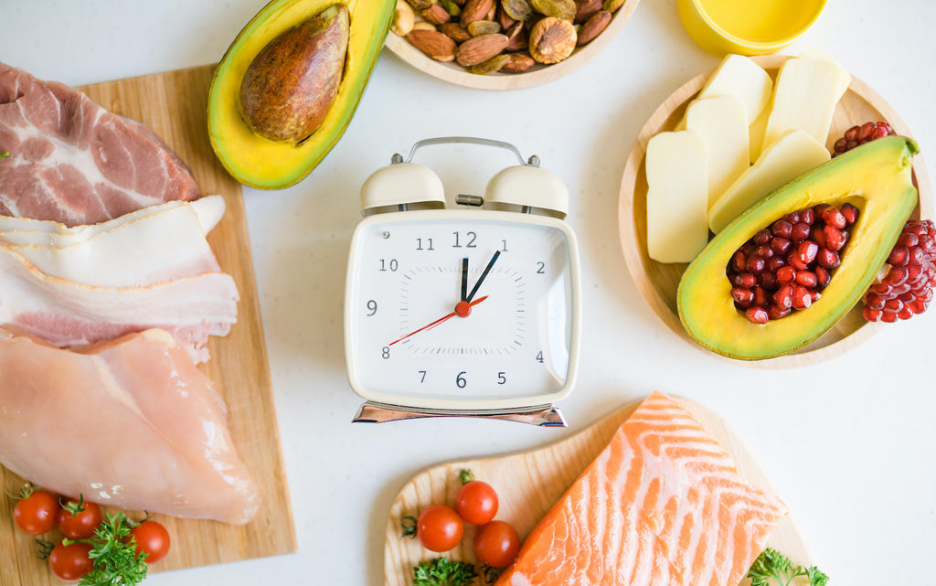 what breaks a fast: Variety of healthy food ingredients with an alarm clock in the middle