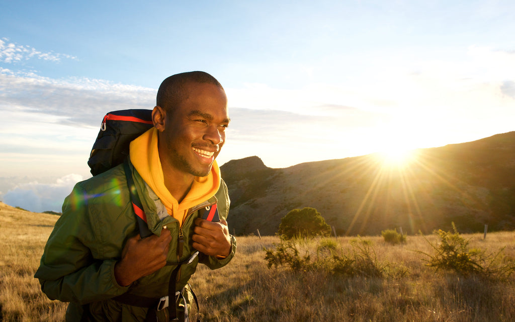 C8 MCT oil: Smiling man walking in the mountains while wearing a backpack