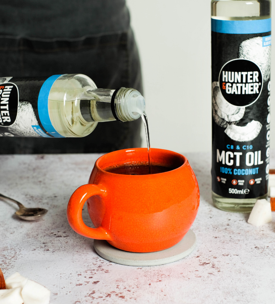 MCT oil being poured from the bottle into a cup of coffee