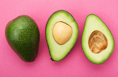 Avocado cut in half on pink background