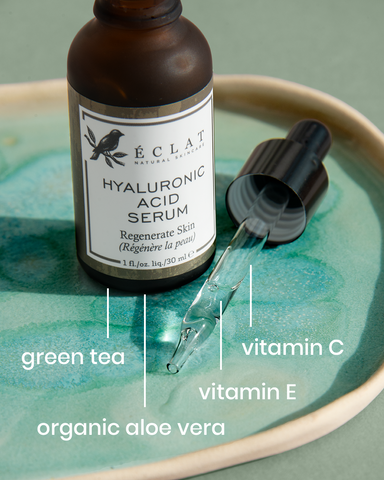 A hyaluronic acid serum bottle with lines pointing from the serum to different ingredient text (green tea, vitamins C &E, and organic aloe vera)