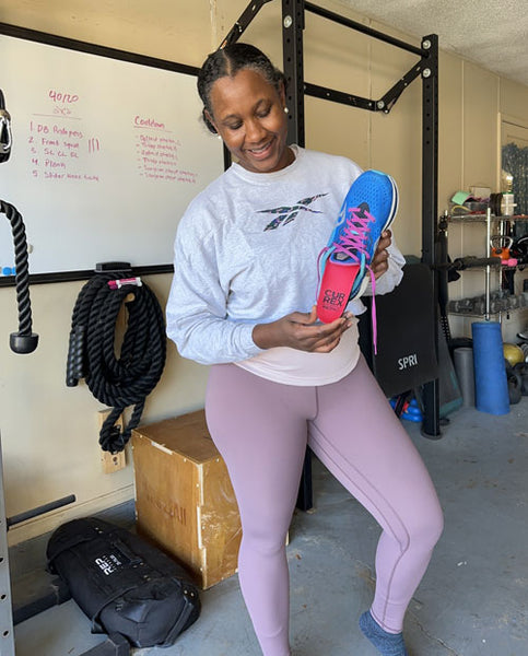 Woman placing red metatarsal support insole into shoe in home gym