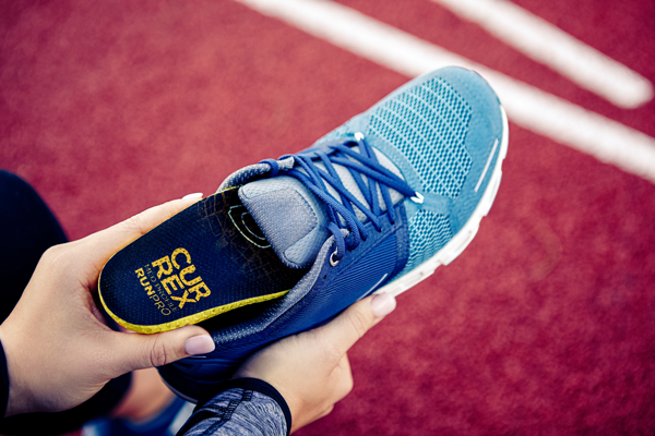 person placing running insole into blue running shoe