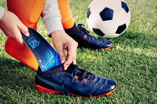 Soccer player putting blue soccer insole into cleats