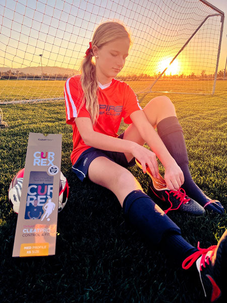 girl's soccer player placing cleat insole into soccer cleat
