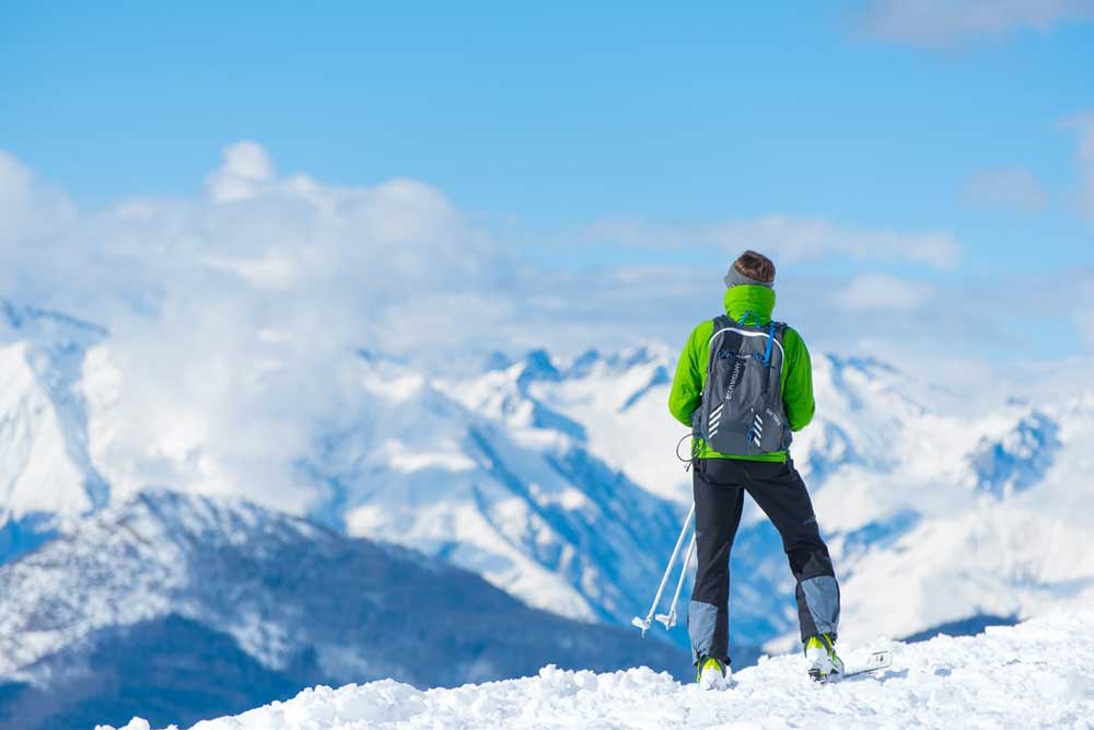 Woman looking at snowy mountains while holding ski poles