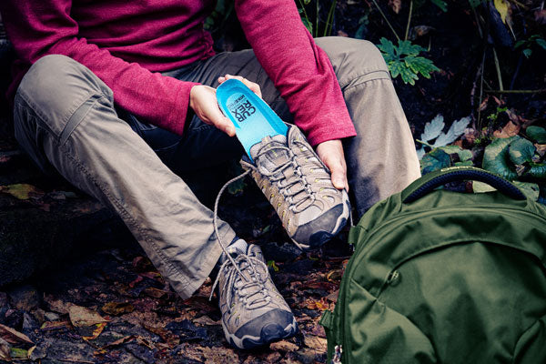 Person placing blue hiking insole into hiking boots
