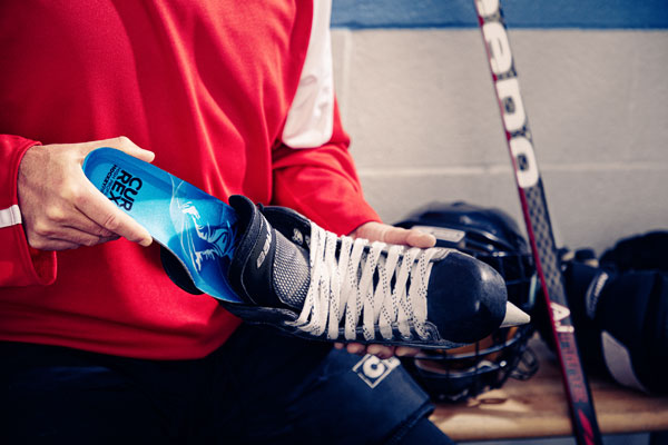 Person placing blue hockey skate insole in hockey skate