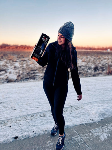 Female runner on snowy path holding CURREX running insoles