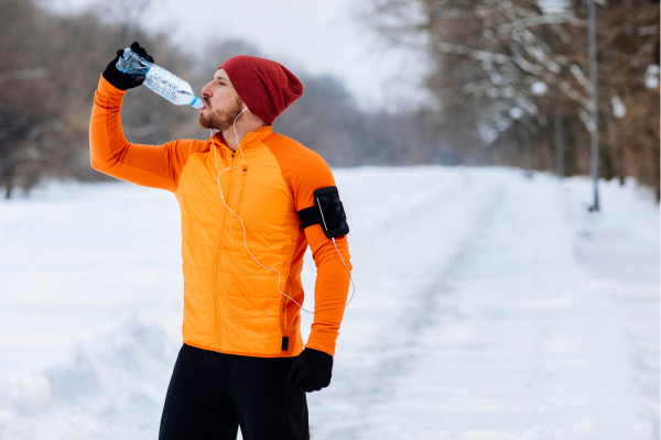 Runner drinking water on a snowy running path