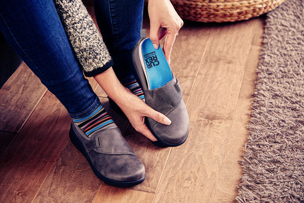 Person placing blue walking insole in gray shoe