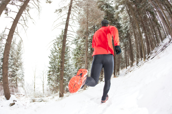 Man trail running outdoors in winter