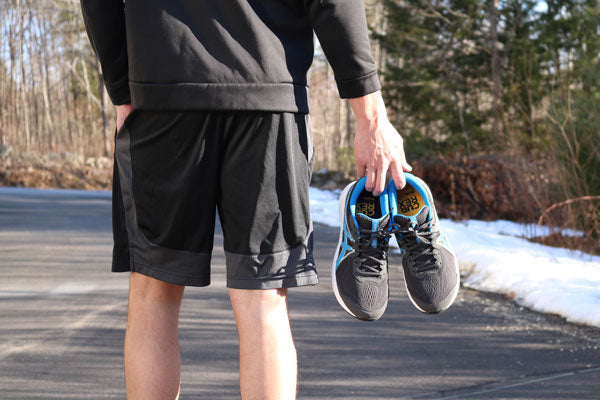 Runner holding running shoes with running insoles outside in winter