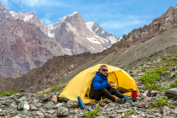 Man eating at campsite on a mountain side