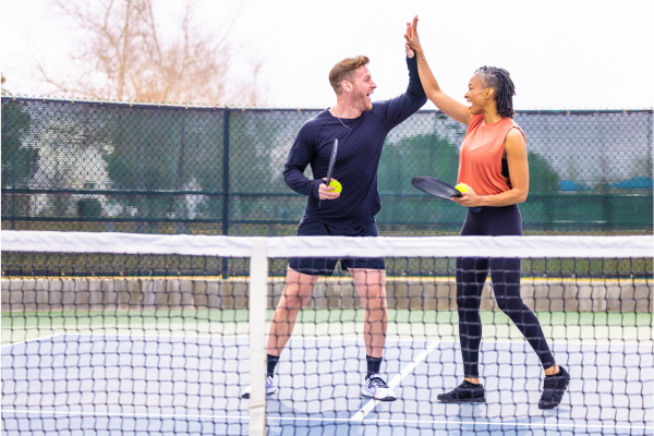 Man and woman high fiving on a pickleball court