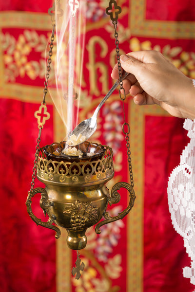 Putting grains of frankincense into a thurible