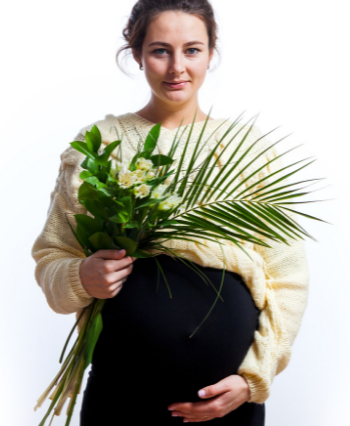 pregnant woman wearing a sweater holding flowers in her hands