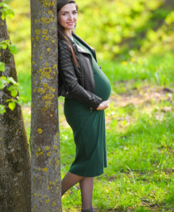 pregnant woman in a green dress standing in the garden