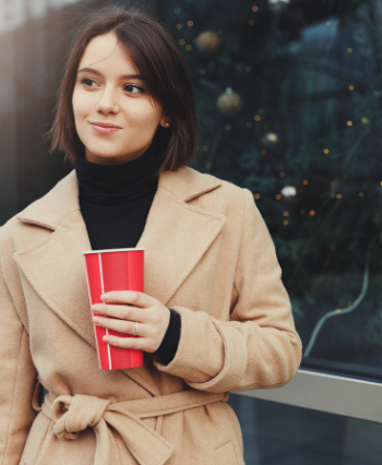 beautiful pregnant woman wearing a coat with a coffee glass