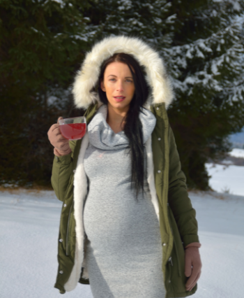 beautiful pregnant woman wearing a green coat with holding a cup